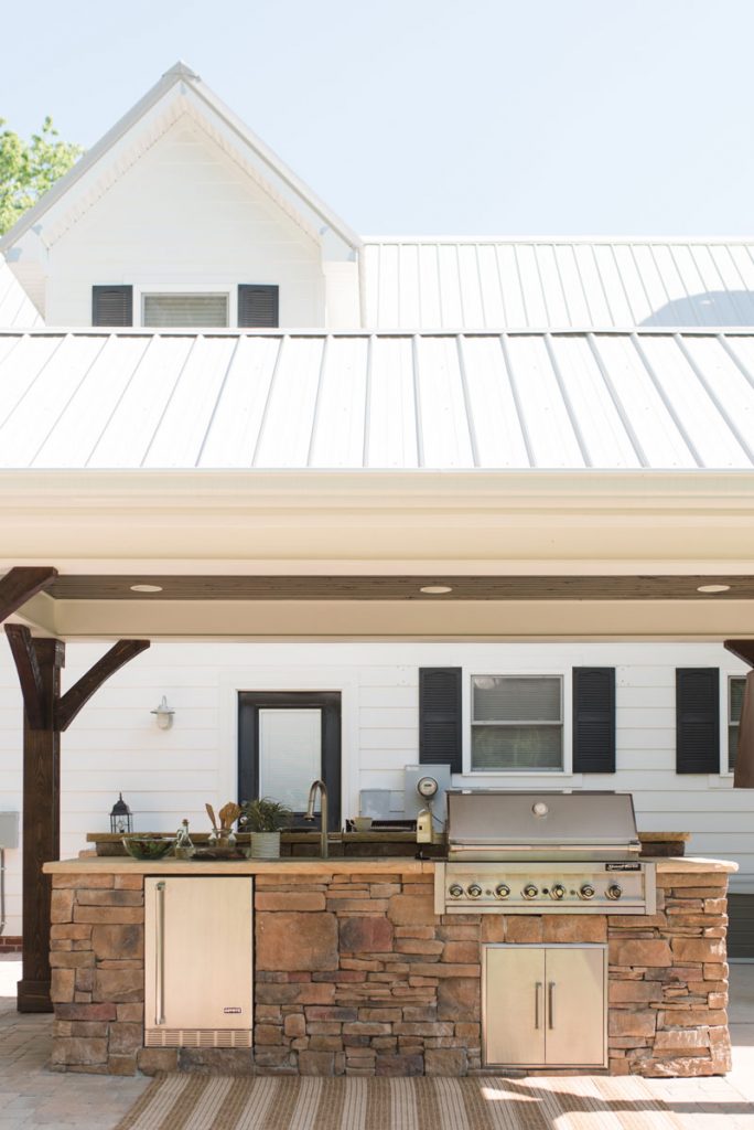 Stone outdoor kitchen with bar seating, natural colors, roof